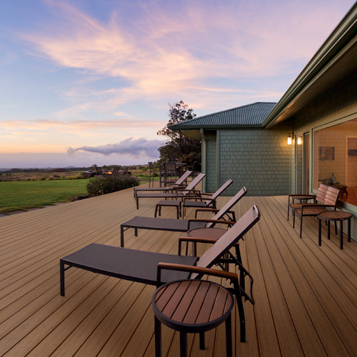 A sprawling composite deck at sunset with lounge chairs in a row