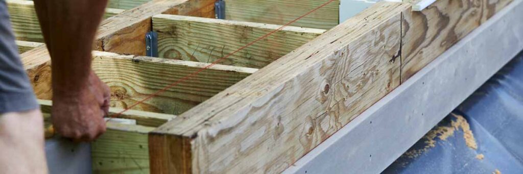 A contractor stretches a red strong across the substructure of a deck