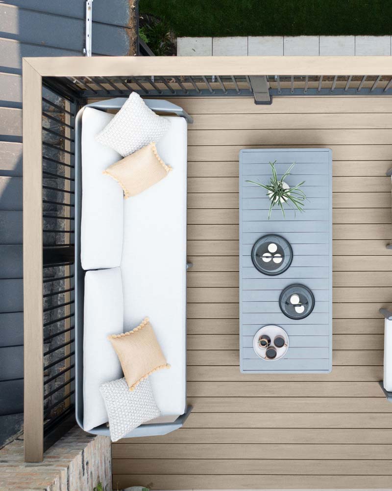 Direct overhead shot of a light gray deck with couch and coffee table